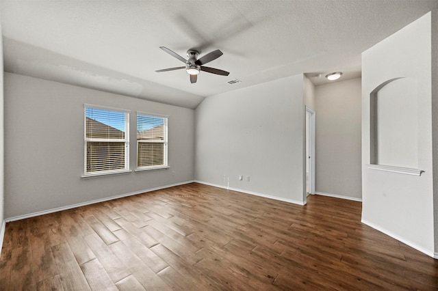 empty room featuring a textured ceiling, dark hardwood / wood-style flooring, vaulted ceiling, and ceiling fan