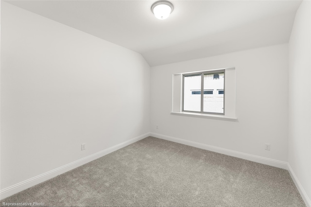 carpeted empty room featuring lofted ceiling