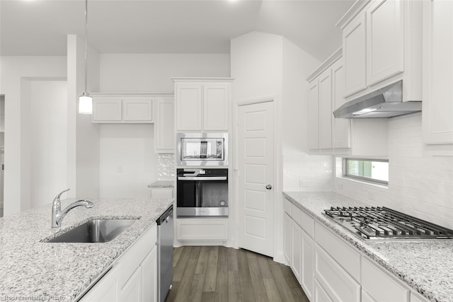 kitchen with decorative light fixtures, white cabinetry, sink, stainless steel appliances, and wall chimney range hood