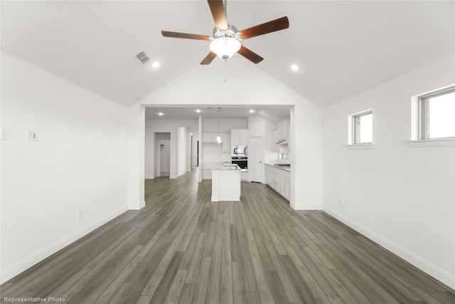 unfurnished living room with ceiling fan, high vaulted ceiling, and dark wood-type flooring