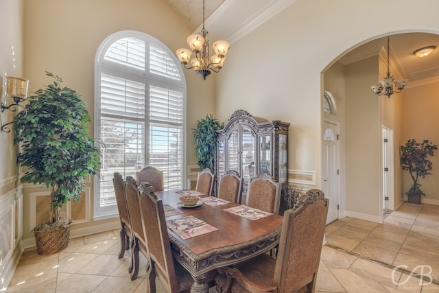 dining area with a chandelier, a high ceiling, light tile patterned floors, and ornamental molding