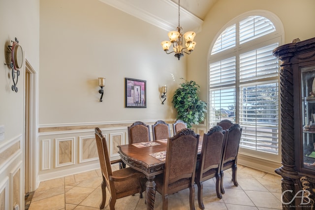 tiled dining area featuring a chandelier, a towering ceiling, and ornamental molding