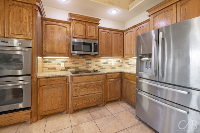 kitchen with backsplash, light stone counters, light tile patterned flooring, and stainless steel appliances