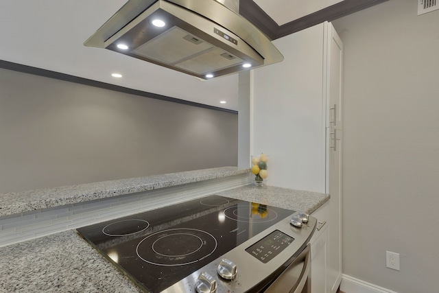 kitchen featuring island range hood, light stone counters, crown molding, and stainless steel range oven