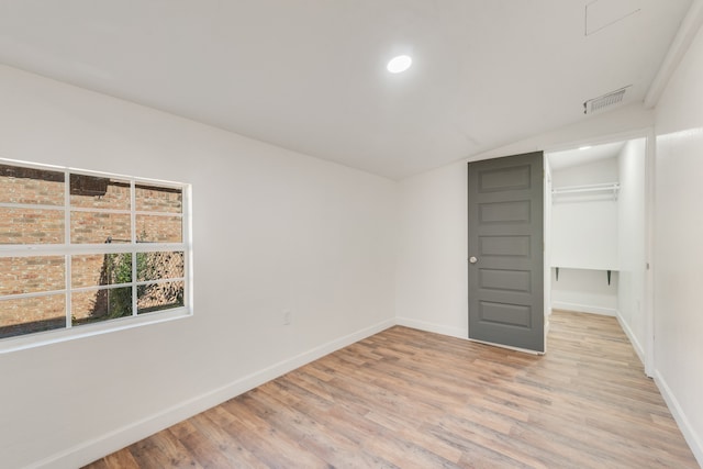 unfurnished bedroom with vaulted ceiling, light wood-type flooring, and a closet