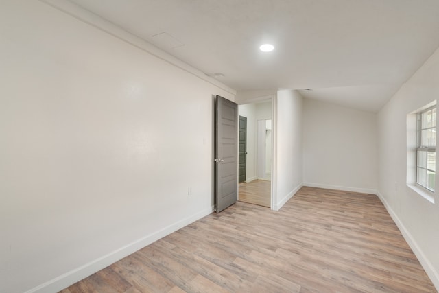 spare room featuring light hardwood / wood-style floors and lofted ceiling