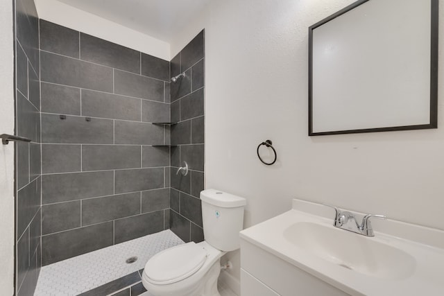 bathroom featuring a tile shower, vanity, and toilet