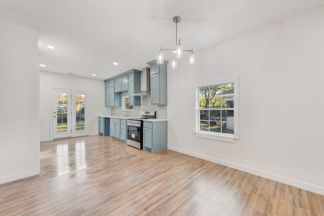 kitchen featuring stainless steel electric range oven, wall chimney range hood, light hardwood / wood-style floors, decorative light fixtures, and decorative backsplash