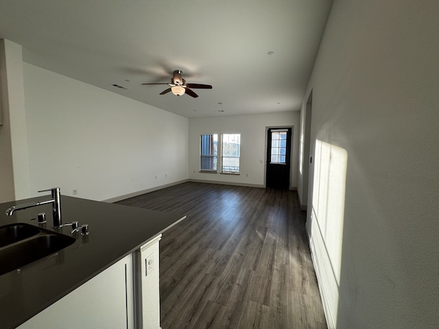 unfurnished living room featuring ceiling fan, sink, and dark hardwood / wood-style floors