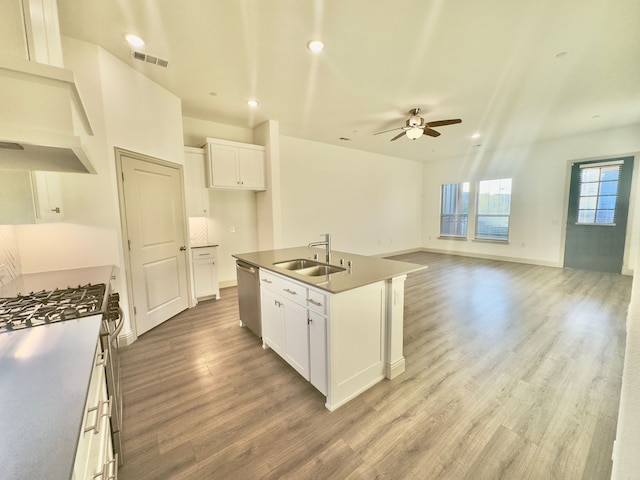 kitchen with a center island with sink, stainless steel dishwasher, white cabinetry, and sink