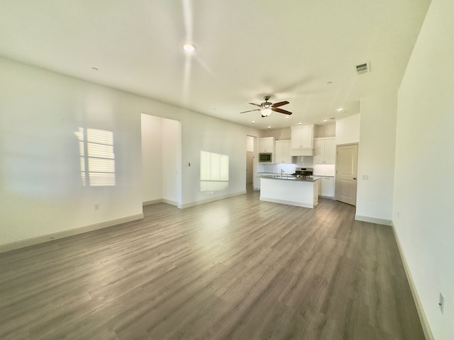 unfurnished living room with ceiling fan, sink, and wood-type flooring