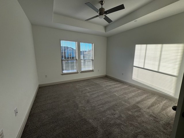 carpeted empty room featuring a raised ceiling and ceiling fan