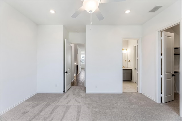 unfurnished bedroom with light carpet, ceiling fan, and ensuite bathroom