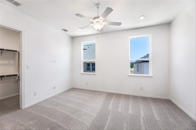 unfurnished bedroom with ceiling fan, a walk in closet, carpet floors, and a closet