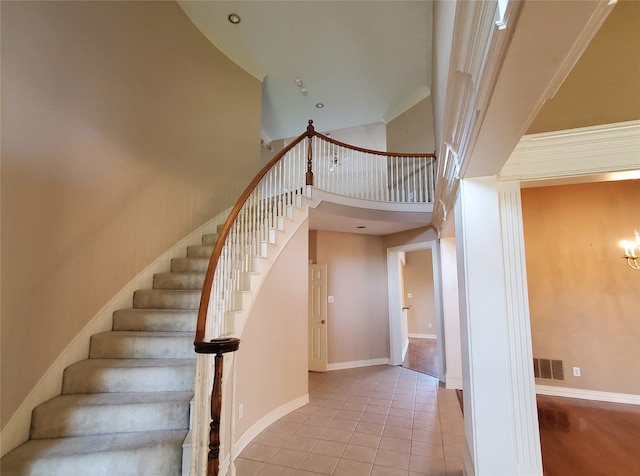 staircase featuring crown molding, tile patterned flooring, and a towering ceiling