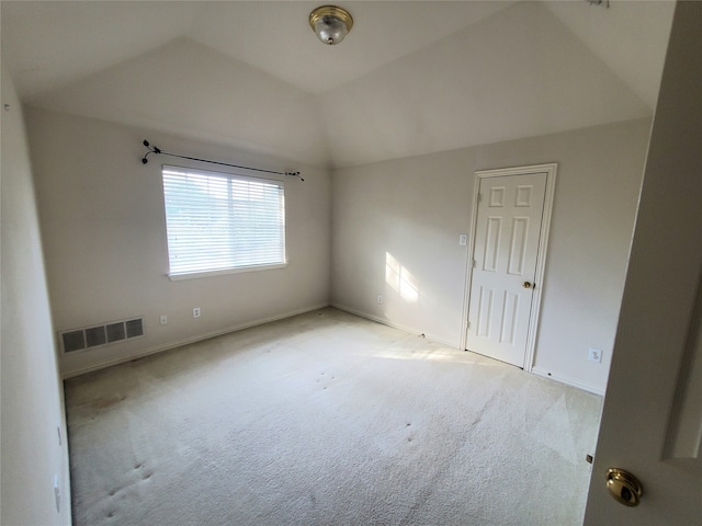 carpeted empty room with vaulted ceiling