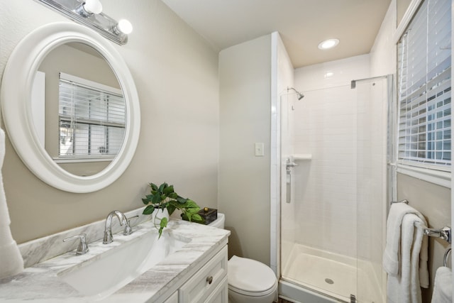 bathroom featuring vanity, toilet, and a shower with shower door