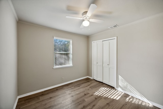 unfurnished bedroom featuring ceiling fan, wood-type flooring, crown molding, and a closet