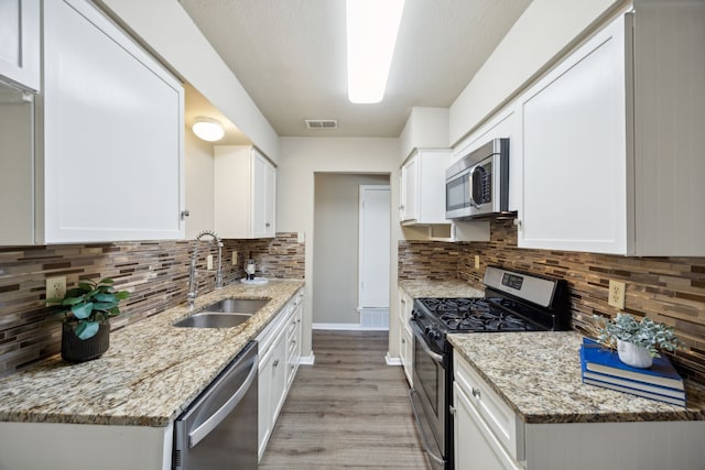 kitchen with appliances with stainless steel finishes, tasteful backsplash, white cabinetry, and sink