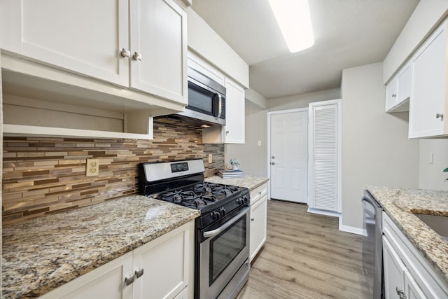 kitchen with light hardwood / wood-style floors, white cabinetry, backsplash, and appliances with stainless steel finishes