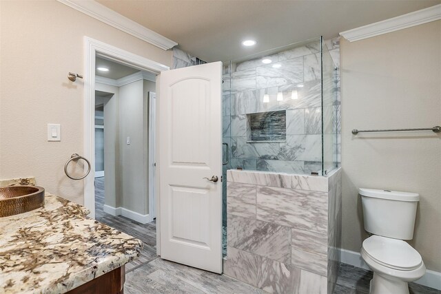 bathroom featuring ornamental molding, an enclosed shower, toilet, vanity, and hardwood / wood-style flooring