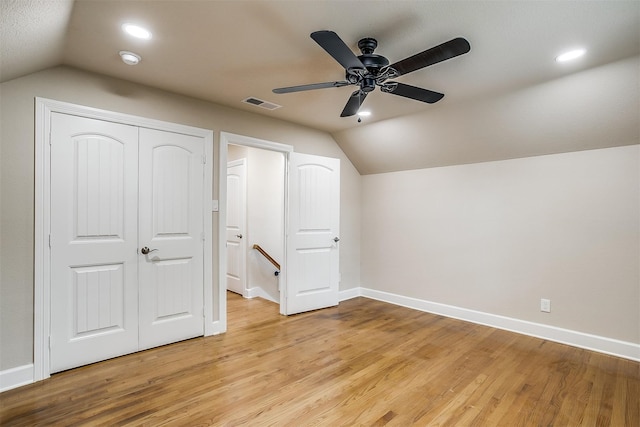 unfurnished bedroom with light wood-type flooring, a closet, ceiling fan, and lofted ceiling