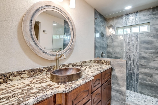 bathroom with tiled shower and vanity