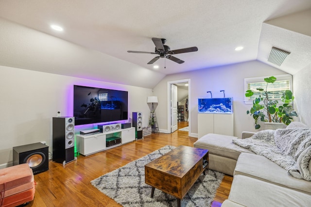 living room with ceiling fan, wood-type flooring, a textured ceiling, and vaulted ceiling