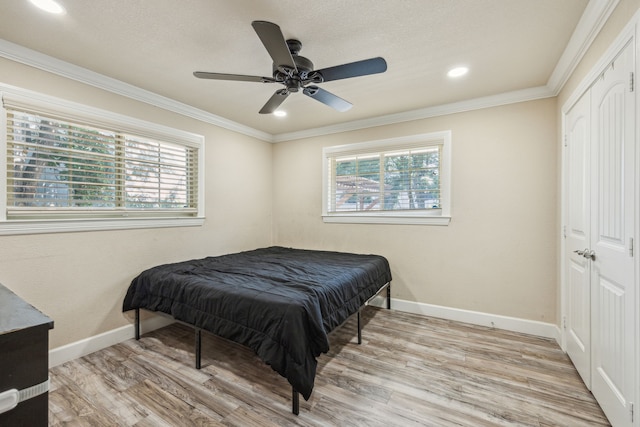 bedroom with ceiling fan, light wood-type flooring, ornamental molding, and a closet