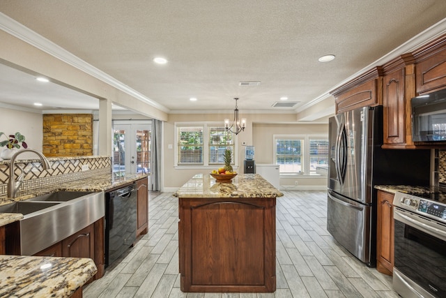 kitchen featuring light wood-type flooring, light stone counters, a kitchen island, and black appliances