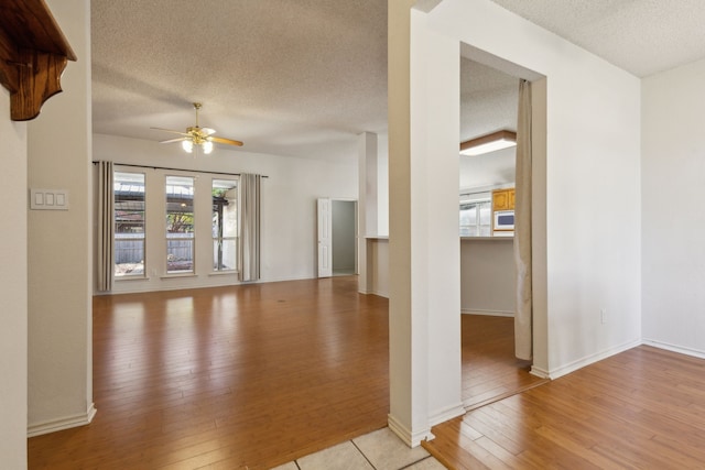1306 Woodmont Dr, Allen, TX 75002 - unfurnished living room with a textured ceiling, light wood-type flooring, ceiling fan, and baseboards