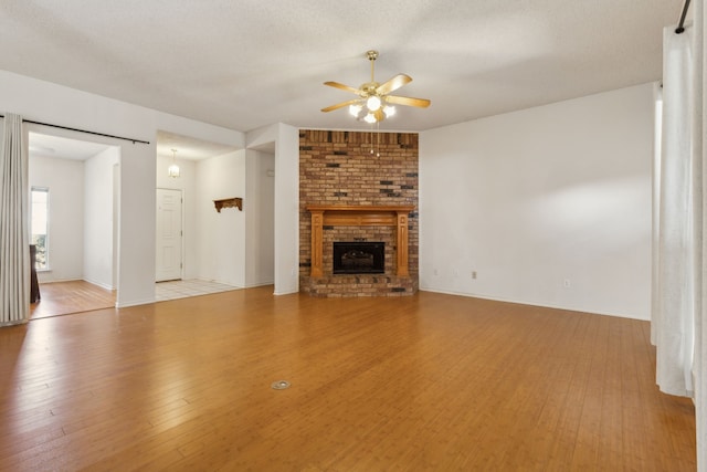1306 Woodmont Dr, Allen, TX 75002 - unfurnished living room featuring ceiling fan, wood finished floors, a brick fireplace, and baseboards