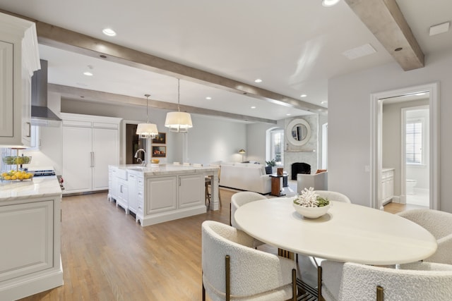 dining room with beam ceiling, light wood-type flooring, and sink