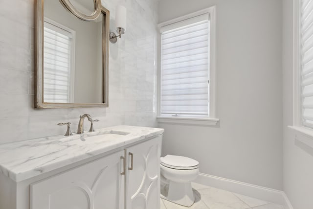 bathroom with vanity, toilet, and a healthy amount of sunlight