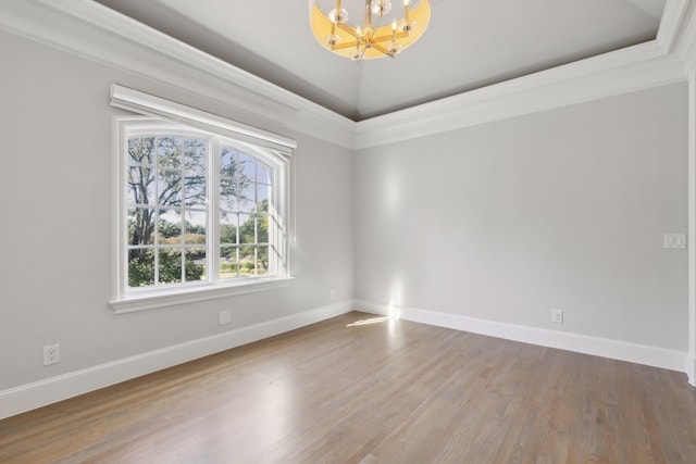 empty room featuring a notable chandelier, crown molding, wood-type flooring, lofted ceiling, and a tray ceiling