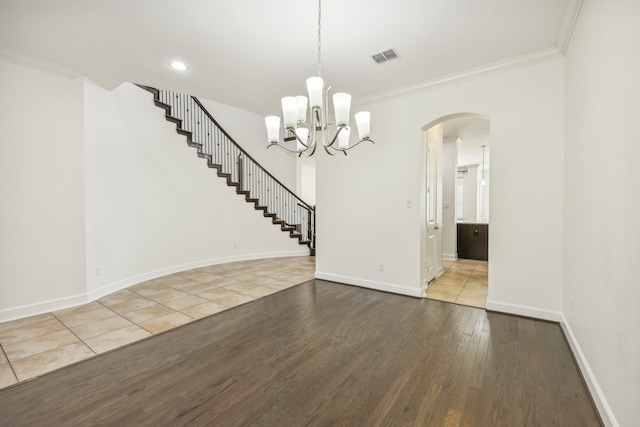 spare room with hardwood / wood-style floors, an inviting chandelier, and ornamental molding