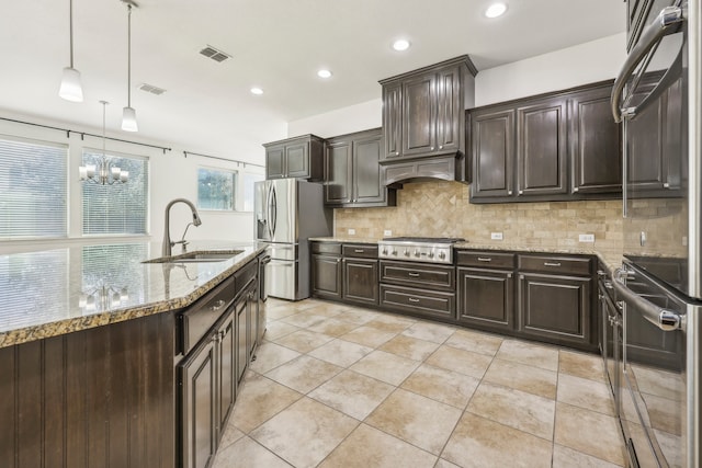 kitchen with hanging light fixtures, sink, appliances with stainless steel finishes, tasteful backsplash, and dark brown cabinets