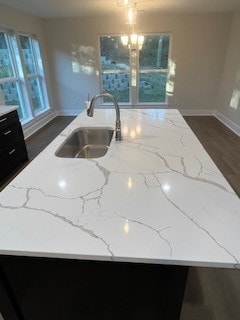 kitchen featuring light stone counters, sink, and an island with sink