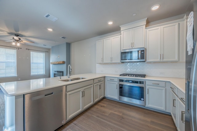 321 Baker Dr, Plano, TX 75074 - kitchen with appliances with stainless steel finishes, a peninsula, a sink, backsplash, and light countertops