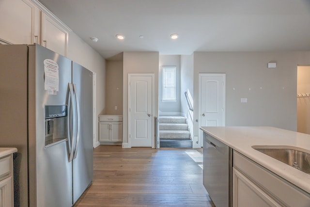 kitchen with white cabinets, light hardwood / wood-style floors, and appliances with stainless steel finishes