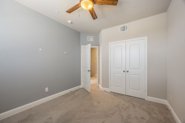 unfurnished bedroom featuring ceiling fan, a closet, and light carpet