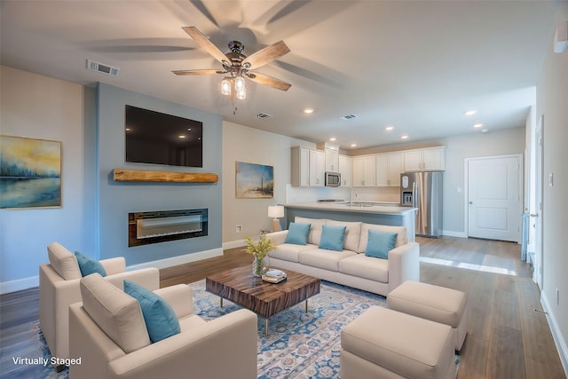 321 Baker Dr, Plano, TX 75074 - living area featuring baseboards, light wood-type flooring, a ceiling fan, recessed lighting, and a glass covered fireplace