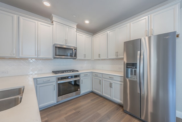 kitchen with sink, stainless steel appliances, tasteful backsplash, dark hardwood / wood-style flooring, and white cabinets