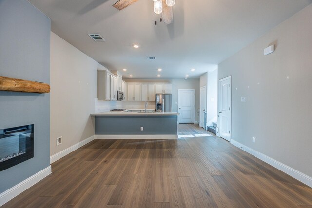 unfurnished living room featuring ceiling fan, sink, and dark wood-type flooring