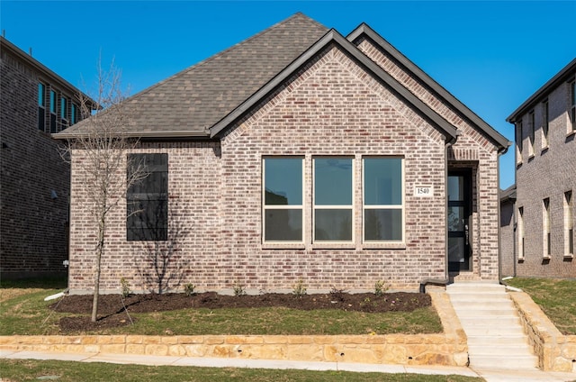 view of front of property with brick siding and a shingled roof