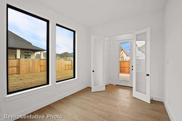 empty room featuring french doors and light hardwood / wood-style floors