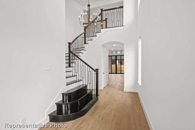 interior space with a towering ceiling, wood-type flooring, and an inviting chandelier