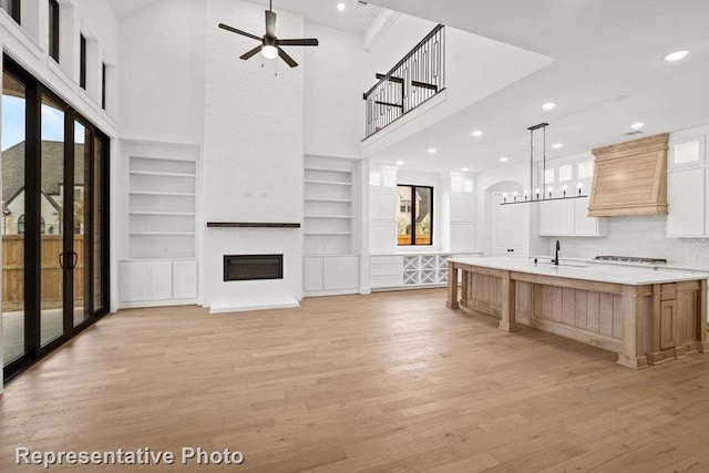 unfurnished living room featuring a wealth of natural light, light hardwood / wood-style flooring, a high ceiling, and sink