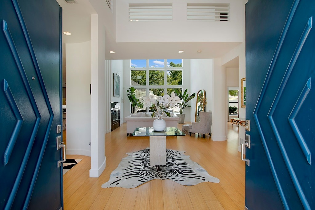 foyer entrance with a towering ceiling and light wood-type flooring