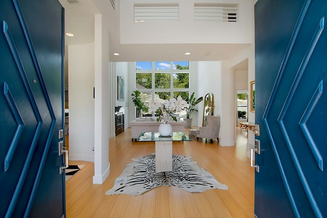 foyer entrance with a towering ceiling and light wood-type flooring